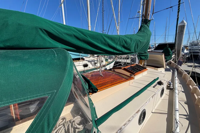 Slide: The Image of 1983 Bristol Channel Cutter 28 sailboat with green covers docked at a marina. - 9