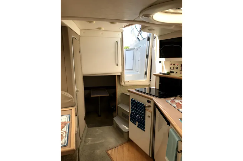 Slide: The Image of Interior of 1997 Maxum 3200 SCR boat, featuring compact kitchen and seating area. - 10
