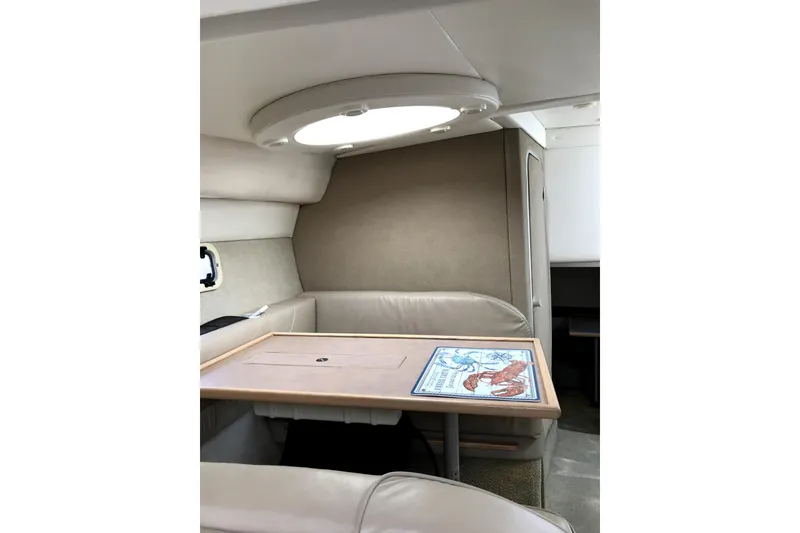 Slide: The Image of Interior of 1997 Maxum 3200 SCR boat with beige seating and a wooden table. - 11