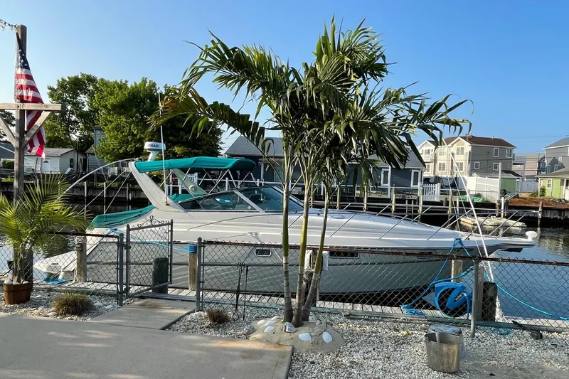 Slide: The Image of 1997 Maxum 3200 SCR boat docked by a waterfront home, surrounded by palm trees. - 3