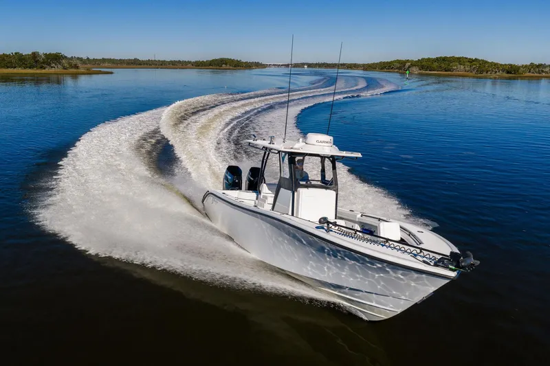 Slide: The Image of 2023 Yellowfin 32 Offshore boat cruising on a calm lake, creating a dynamic wake. - 17
