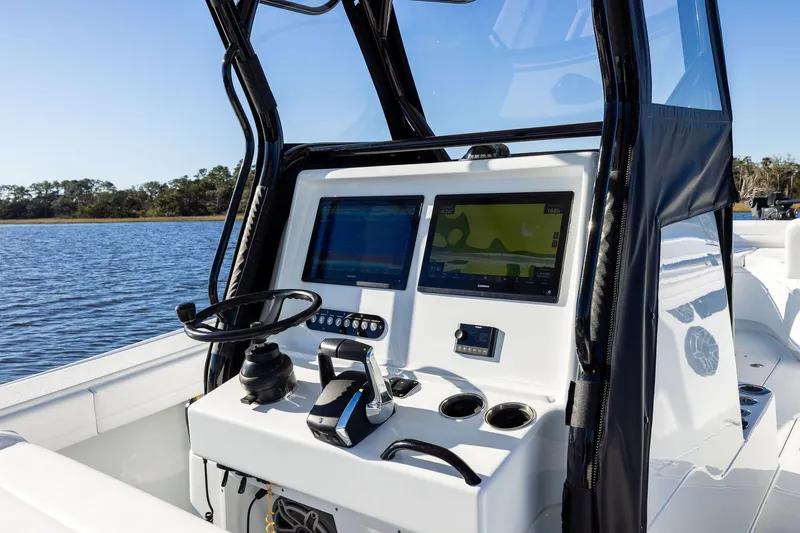 Slide: The Image of 2023 Yellowfin 32 Offshore boat console with dual navigation screens on calm water. - 38