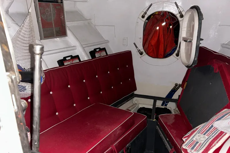 Slide: The Image of Interior of a 1963 Motor Life Boat 44 with red seating and porthole. - 14
