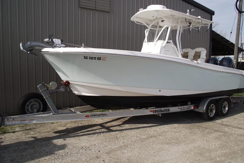 Slide: The Image of 2019 Edgewater 245CC boat on trailer, parked outdoors near a building. - 1