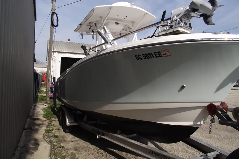 Slide: The Image of 2019 Edgewater 245CC boat on trailer, parked beside a building. - 2