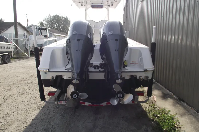 Slide: The Image of 2019 Edgewater 245CC boat with dual outboard motors, parked near a metal building. - 3