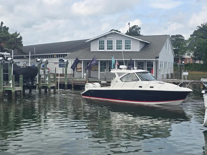 Slide: The Image of 2025 Pursuit OS 325 Offshore boat docked near a marina building. - 10
