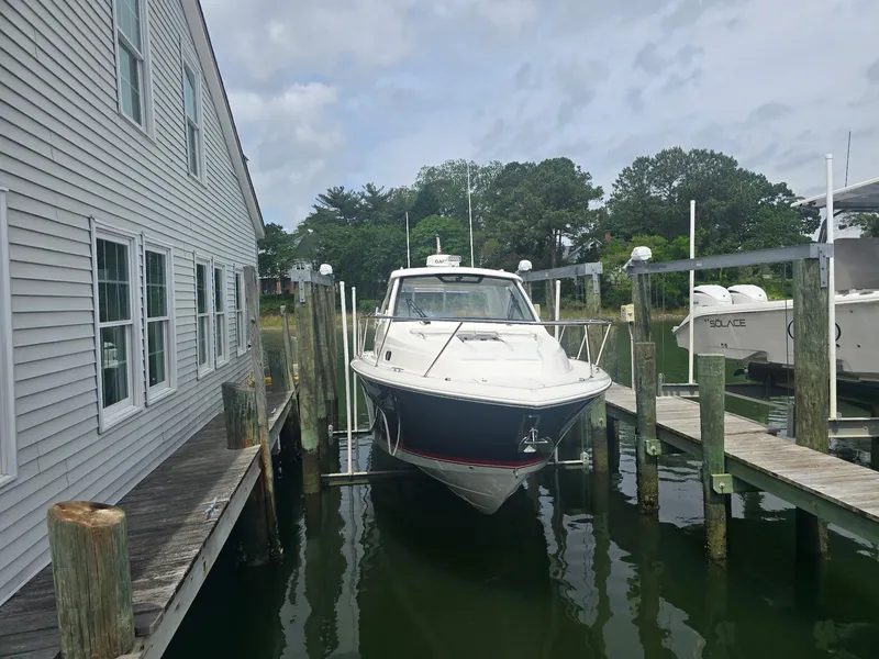 Slide: The Image of 2025 Pursuit OS 325 Offshore boat docked near a building, surrounded by calm water. - 11