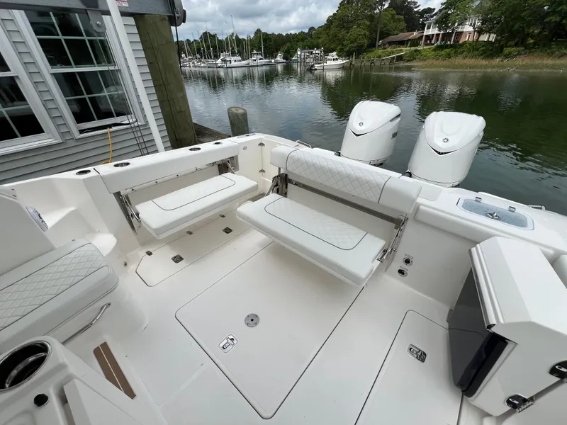 Slide: The Image of 2025 Pursuit OS 325 Offshore boat interior with seating, docked by a serene waterfront. - 12