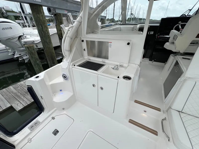Slide: The Image of 2025 Pursuit OS 325 Offshore boat interior with kitchenette and seating area. - 14
