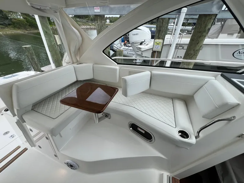 Slide: The Image of 2025 Pursuit OS 325 Offshore boat interior with white seating and wooden table. - 15