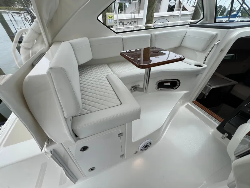 Slide: The Image of 2025 Pursuit OS 325 Offshore boat interior with white seating and a small wooden table. - 16