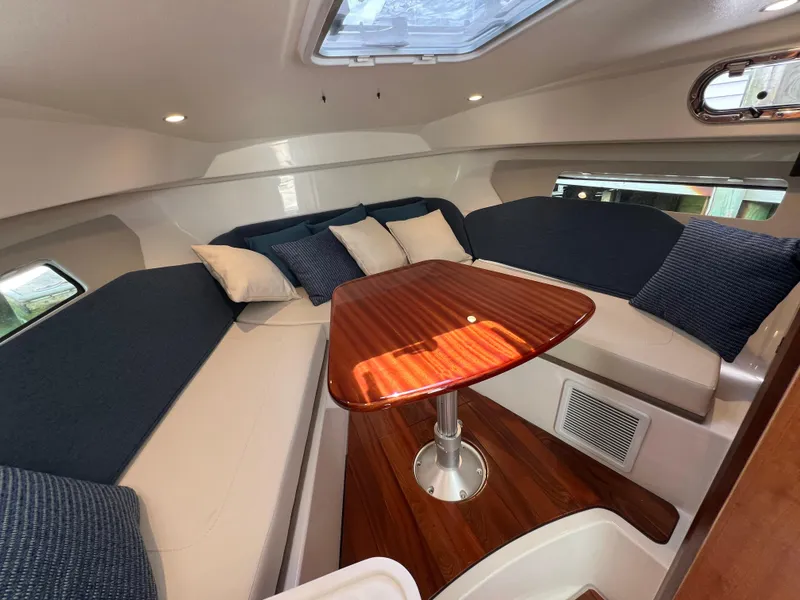 Slide: The Image of 2025 Pursuit OS 325 Offshore cabin with elegant seating and wooden table. - 22