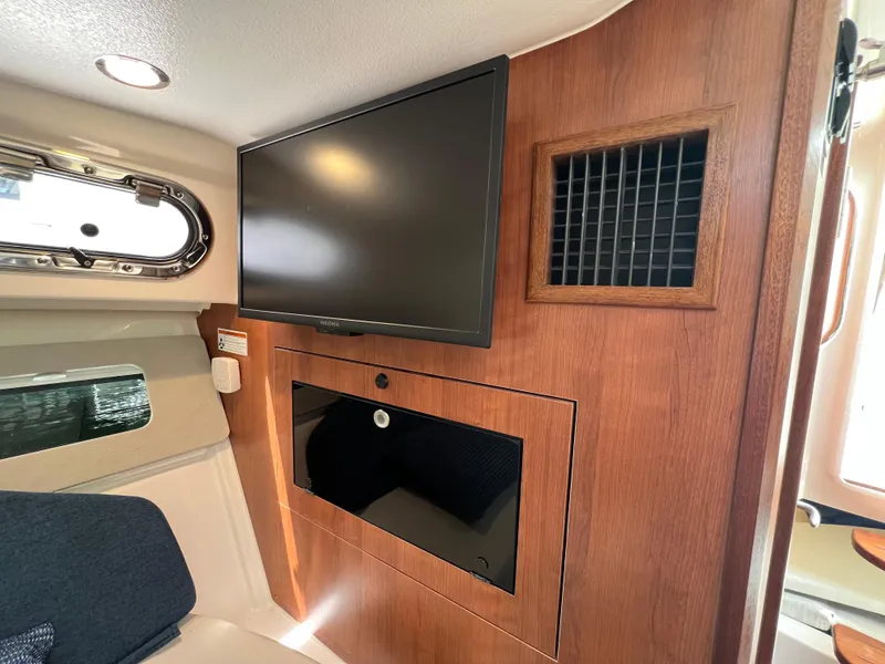 Slide: The Image of 2025 Pursuit OS 325 Offshore cabin interior with TV and wood paneling. - 24