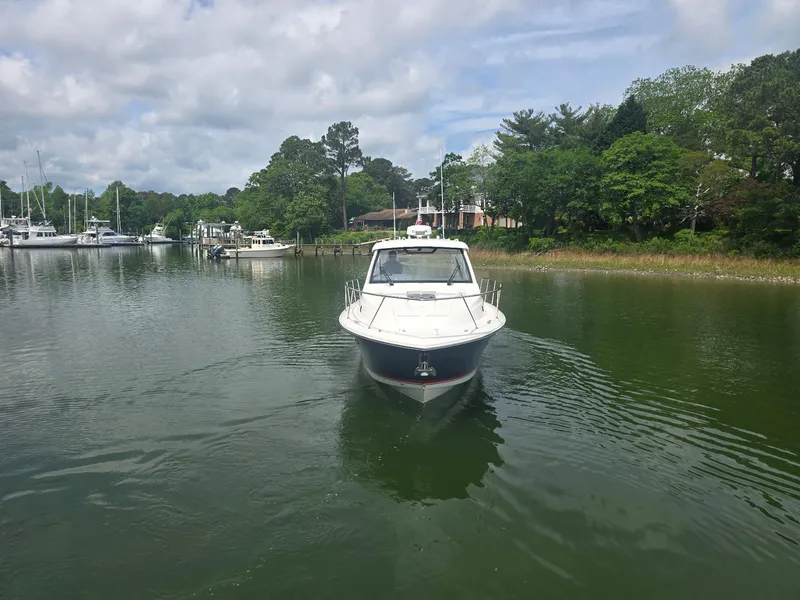 Slide: The Image of 2025 Pursuit OS 325 Offshore boat cruising on a calm, tree-lined waterway. - 3