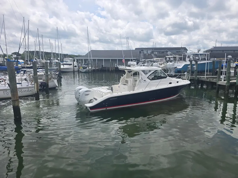 Slide: The Image of 2025 Pursuit OS 325 Offshore boat docked in a marina under cloudy skies. - 8
