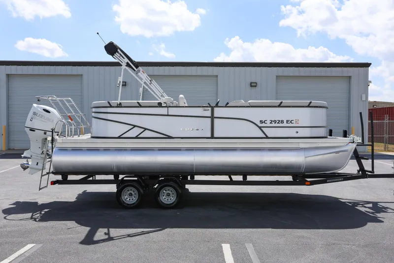 Slide: The Image of 2023 Crest Classic LX 220 SLC pontoon boat on trailer, parked outdoors. - 1