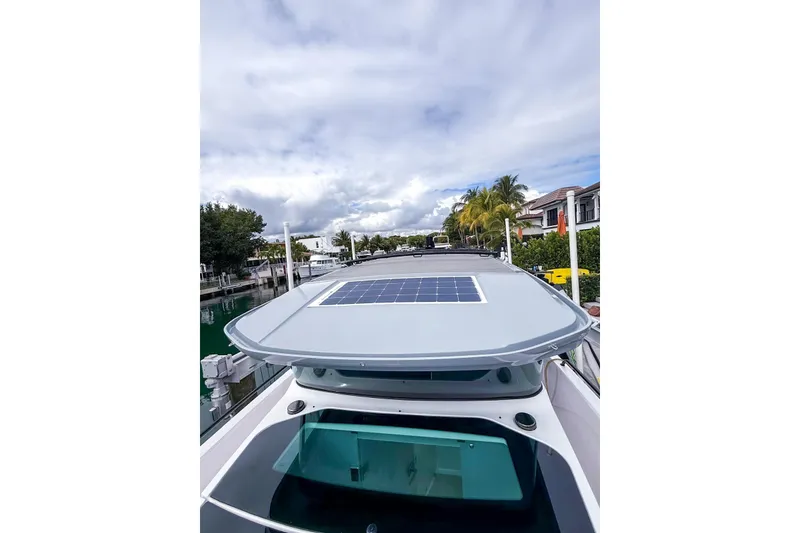 Slide: The Image of 2023 Axopar 37 XC Cross Cabin with solar panel on roof, docked by waterfront homes. - 25