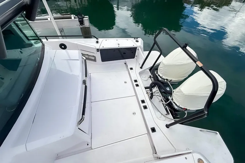 Slide: The Image of 2023 Axopar 37 XC Cross Cabin boat deck with covered engines, docked on calm water. - 4