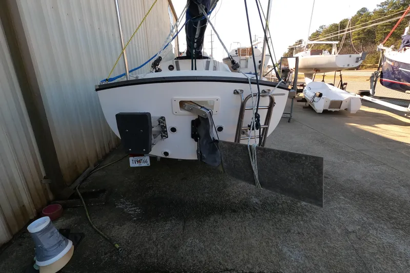 Slide: The Image of 2023 Com-Pac Sunday Cat sailboat rear view in a boatyard setting. - 2