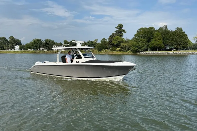 The Image of 2021 Pursuit S 328 Sport boat cruising on a calm lake with trees in the background. - 1