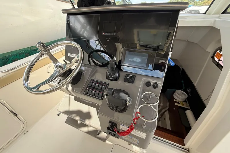 Slide: The Image of 2021 Pursuit S 328 Sport boat helm with steering wheel and navigation controls. - 7