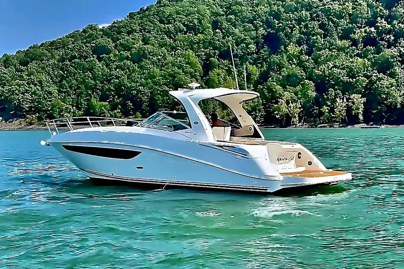 Slide: The Image of 2016 Sea Ray Sundancer 370 yacht cruising on a serene lake with lush green hills. - 4