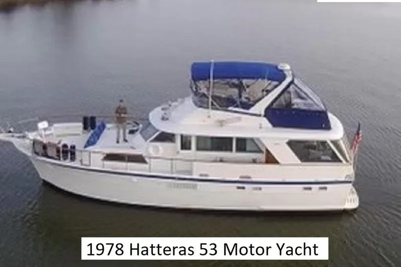 The Image of 1978 Hatteras 53 Motor Yacht on calm water, featuring blue accents and spacious deck. - 0