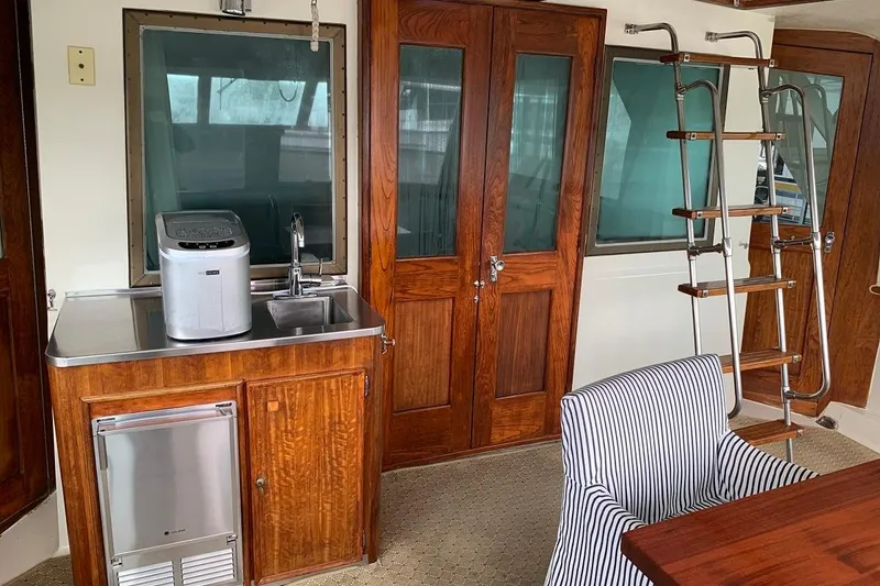 Slide: The Image of 1978 Hatteras 53 Motor Yacht interior with kitchenette, wooden cabinetry, and striped chair. - 23