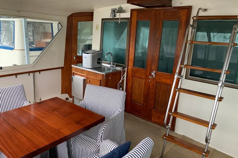 Slide: The Image of Interior of 1978 Hatteras 53 Motor Yacht with wooden table, striped chairs, and kitchenette. - 24