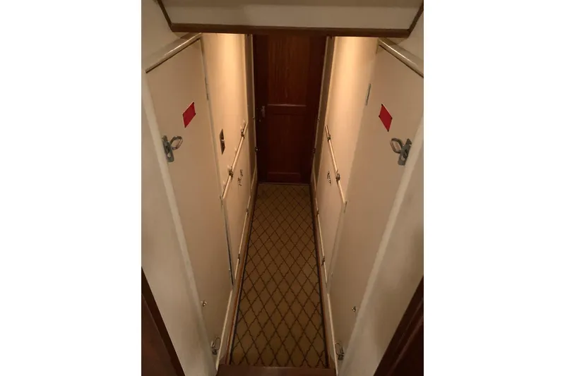 Slide: The Image of Narrow hallway inside 1978 Hatteras 53 Motor Yacht with patterned carpet and closed doors. - 52