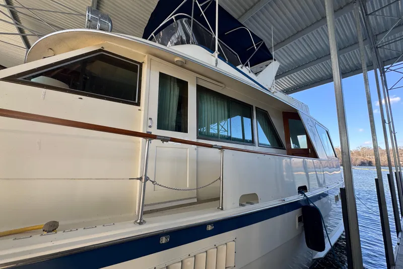 Slide: The Image of 1978 Hatteras 53 Motor Yacht docked under a covered marina with scenic water view. - 9