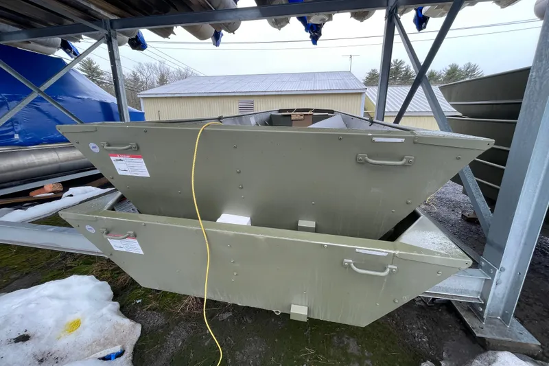 Slide: The Image of Outdoor storage of Lund 1648M boat hulls, 2026 model, in a snowy yard. - 2