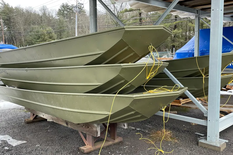 Slide: The Image of Stacked 2026 Lund 1648M boats in storage, featuring green hulls and yellow ropes. - 6