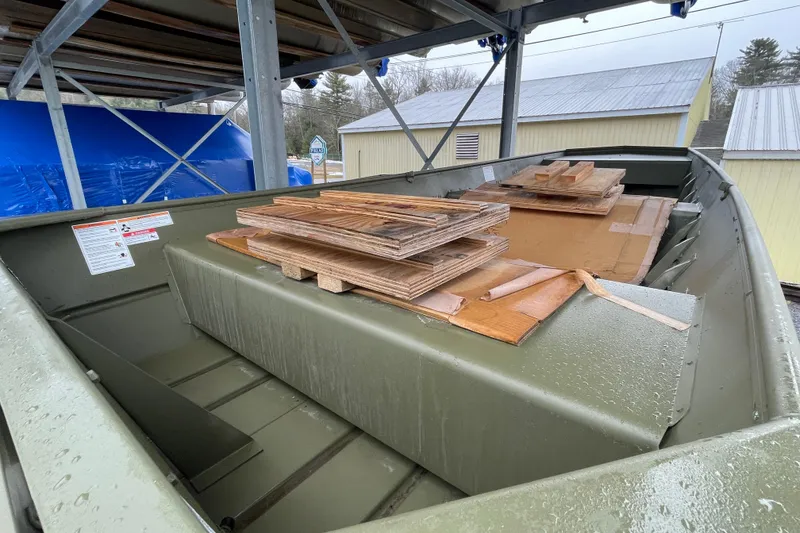 Slide: The Image of 2026 Lund 1648M boat with wooden pallets, stored under a metal structure. - 9