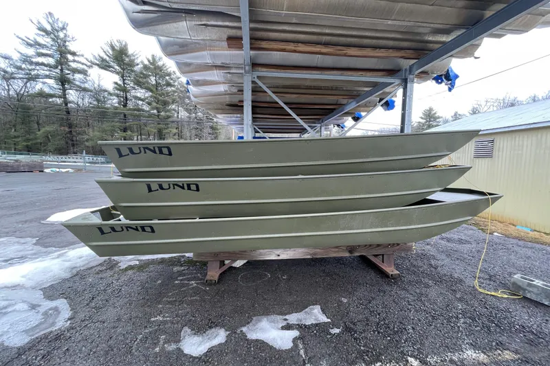 The Image of Stacked 2026 Lund 1852MT boats under shelter, outdoor storage setting. - 0