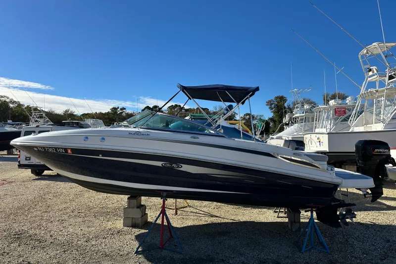 Slide: The Image of 2011 Sea Ray 240 Sundeck boat on stands in a marina under clear blue sky. - 1