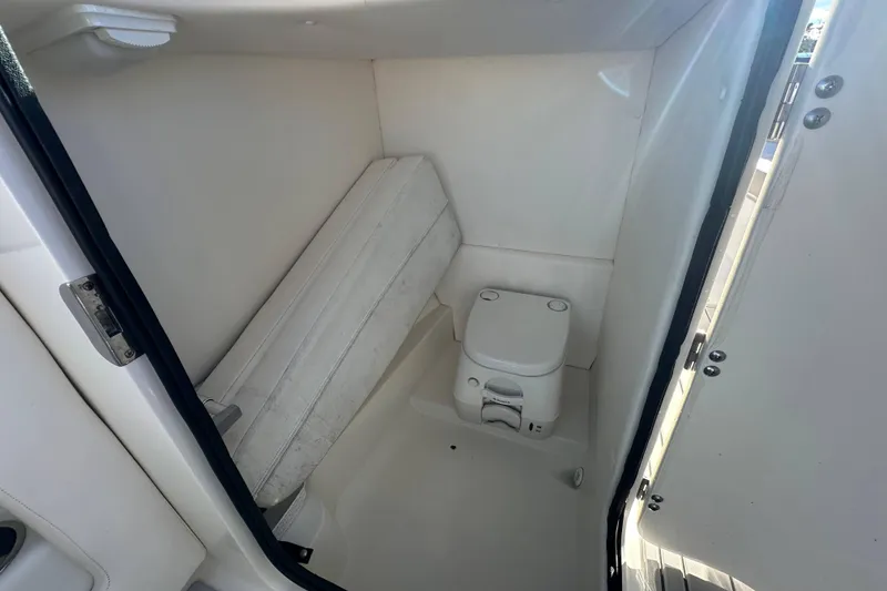 Slide: The Image of 2011 Sea Ray 240 Sundeck interior with compact marine toilet and storage area. - 11