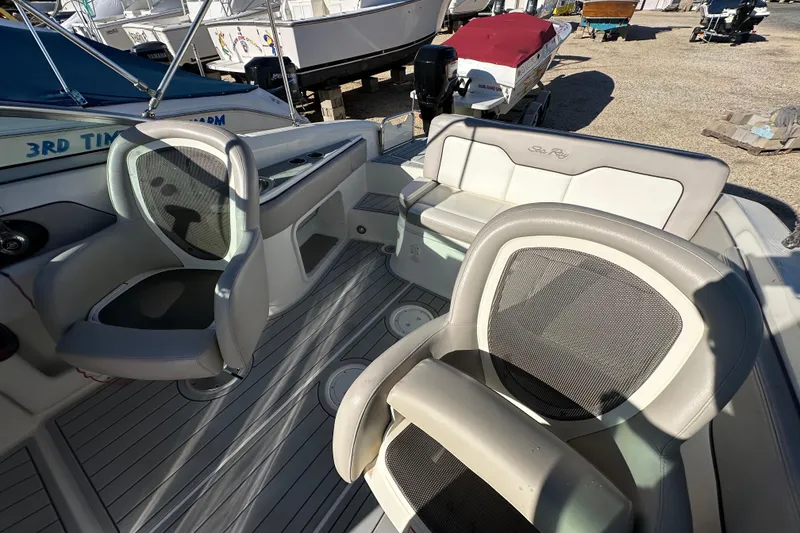Slide: The Image of 2011 Sea Ray 240 Sundeck interior with seating and helm, docked outdoors. - 17