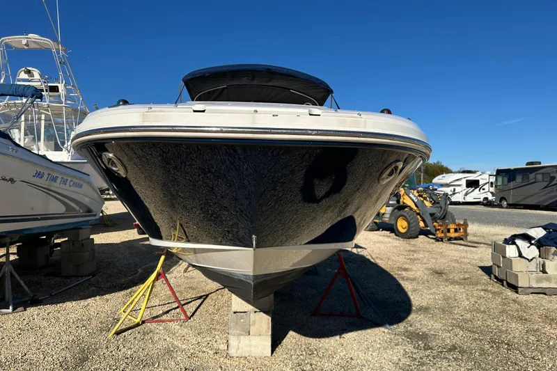 Slide: The Image of 2011 Sea Ray 240 Sundeck boat on stands, parked outdoors under clear blue sky. - 3