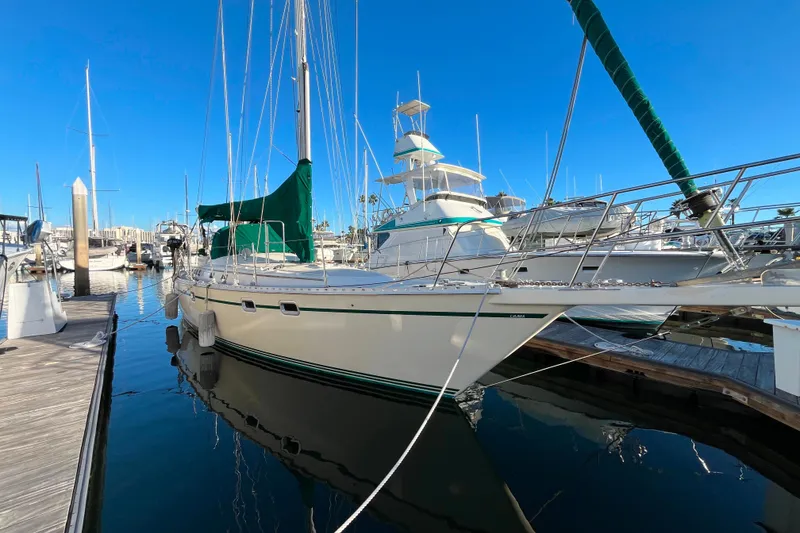 The Image of 1985 Caliber 47LRC sailboat docked at marina under clear blue sky. - 0