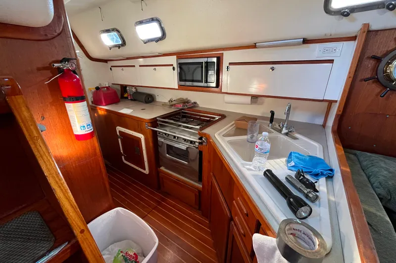 Slide: The Image of Interior of 1985 Caliber 47LRC sailboat kitchen with stove, sink, and wooden cabinetry. - 10
