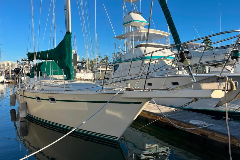 Slide: The Image of 1985 Caliber 47LRC sailboat docked at marina under clear blue sky. - 2