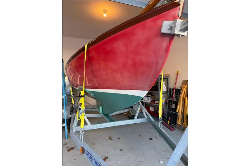 Slide: The Image of Red and green Herreshoff 12 1/2 sailboat from 2002 on a trailer in a garage. - 11