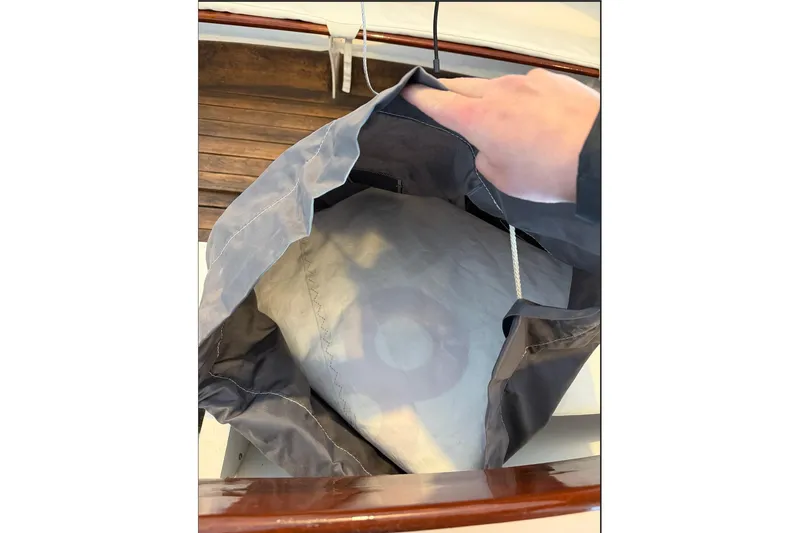 Slide: The Image of Hand holding a sail bag on a 2002 Herreshoff 12 1/2 sailboat. - 13