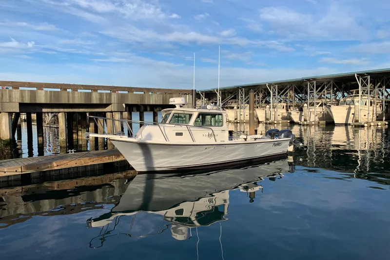 Slide: The Image of 2019 Parker 2820 XLD Sport Cabin boat docked at marina under blue sky. - 2