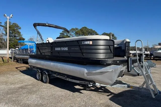 The Image of 2022 Sweetwater 2286 pontoon boat on trailer, parked outdoors under clear blue sky. - 1