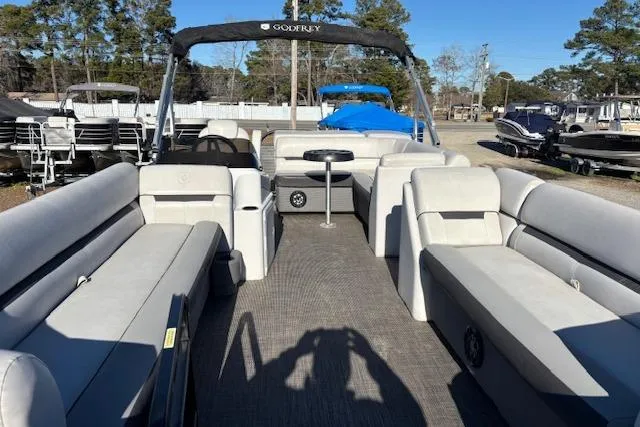 Slide: The Image of 2022 Sweetwater 2286 pontoon boat with spacious seating and canopy, parked outdoors. - 8
