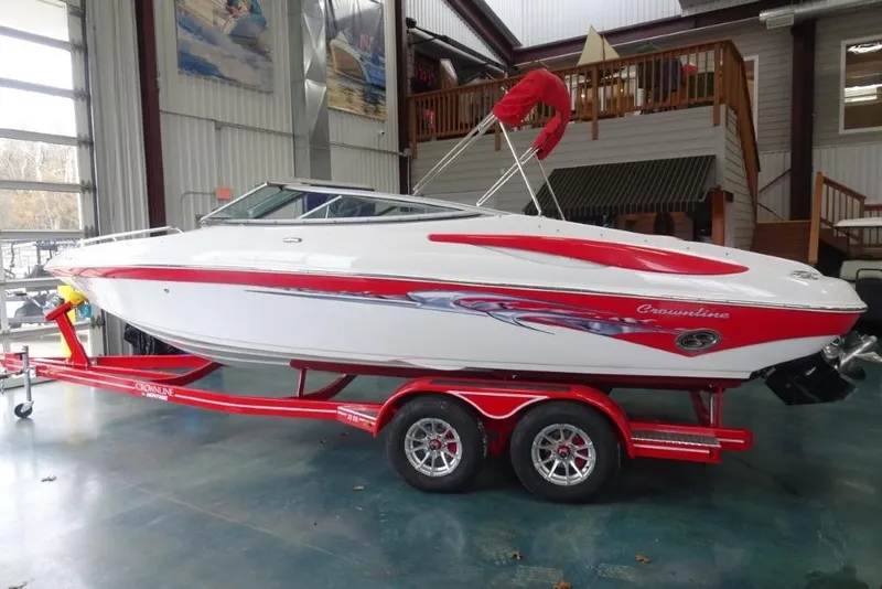 Slide: The Image of 2008 Crownline 23 SS boat with red accents on a matching trailer in a showroom. - 1