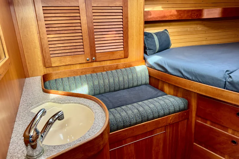 Slide: The Image of Cozy Sabre 402 yacht interior with wooden cabinetry, sink, and cushioned seating, year 2000 model. - 23